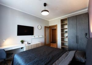 a bedroom with a bed and a desk and a tv at Stylish apartment with parking & spacious balcony in Rīga