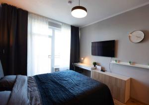 a bedroom with a bed and a flat screen tv at Stylish apartment with parking & spacious balcony in Riga