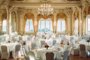 Habitación con mesas y sillas blancas y lámpara de araña. en Grand Hotel Suisse Majestic, Autograph Collection en Montreux