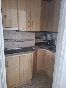 una pequeña cocina con armarios de madera en una habitación en moriones en Torrevieja