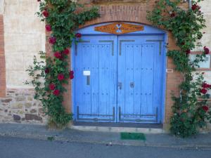 une porte bleue sur un bâtiment en briques avec des roses dans l'établissement Hotel Rural La Rosa de los Tiempos, à Carneros