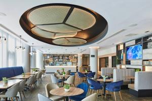 ロンドンにあるResidence Inn by Marriott London Kensingtonのテーブルと椅子があり、天井が高いレストラン