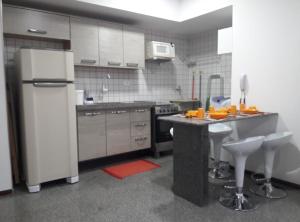 een keuken met een koelkast en een tafel. bij Excelente quarto/sala in Maceió