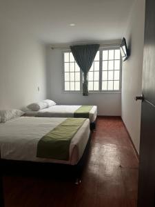two beds in a room with two windows at Hotel Artistico in Bogotá