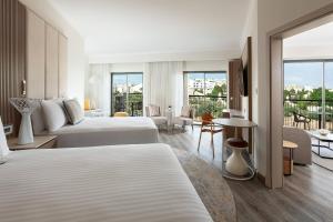 a hotel room with two beds and a balcony at Malta Marriott Resort & Spa in St. Julianʼs