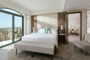 a bedroom with a white bed and a balcony at Malta Marriott Resort & Spa in St. Julianʼs