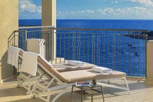 a balcony with a table and chairs and the ocean at Malta Marriott Resort & Spa in St. Julianʼs