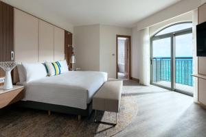 a bedroom with a bed and a view of the ocean at Malta Marriott Resort & Spa in St. Julianʼs