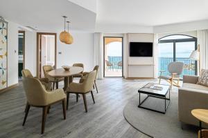 a living room with a table and chairs and a couch at Malta Marriott Resort & Spa in St. Julianʼs