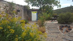 einen Garten mit gelben Blumen und ein Steingebäude in der Unterkunft Gîte dans ancienne bergerie en pleine garrigue in Fraissé-des-Corbières