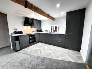 a kitchen with black cabinets and a white floor at The Penthouse, top floor of a Grade II Listed Mill in Praze an Beeble