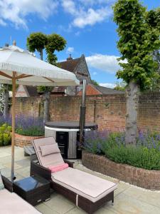a patio with an umbrella and chairs and a grill at The Pool House in Henley on Thames