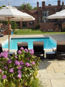 een zwembad met 2 stoelen en paarse bloemen bij The Pool House in Henley on Thames