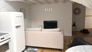 a living room with a white couch and a tv at Maison Bossoreil - appartement Aubance in Angers