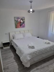 ein Schlafzimmer mit einem weißen Bett und zwei Hausschuhen darauf in der Unterkunft Green Nest in Brezoi