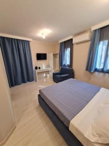 a bedroom with a bed and a chair and blue curtains at EPONIMI ROOMs in Taormina