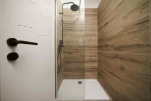 a shower with a glass door and wooden wall at Apartments Picikato in Bilice +82 photos