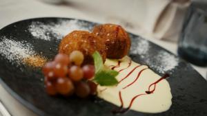 a black plate with a dessert with grapes on it at Hotel Hubertusstube in Laion