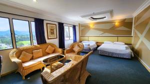um quarto de hotel com duas camas e um sofá e cadeiras em Fair Park Hotel em Ipoh
