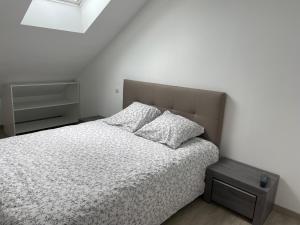 een slaapkamer met een bed met witte lakens en kussens bij Appartement centre ville - Sablé sur Sarthe in Sablé-sur-Sarthe