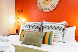 1 cama con almohadas blancas y pared de color naranja en Derbyshire Rustic Bohemian, en Cleveland Heights