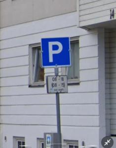 una señal azul de estacionamiento en un poste frente a un edificio en Jennifers Place, en Trondheim