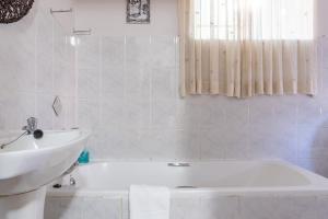 uma casa de banho com um lavatório e uma banheira e um lavatório em El Sali Guest House em Hilton