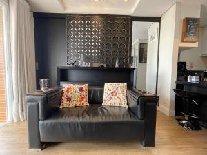 un sofá de cuero negro en una sala de estar con piano en Studio Deluxe - Dot 173 en Campinas
