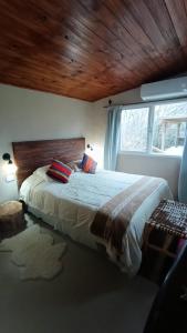 1 dormitorio con 1 cama grande y techo de madera en El campito en Capilla del Señor