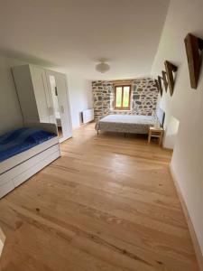 1 dormitorio con 1 cama y suelo de madera en Domaine des Hiboux en Chastreix
