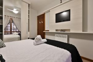a bedroom with a bed and a tv on a wall at Apartamento de 1 quarto in Gramado