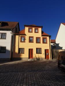 a yellow house with red doors on a brick street at Ferienwohnung ,,Hinter der Mauer'' in Hildburghausen