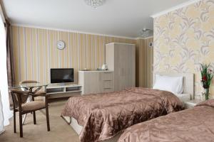 a hotel room with two beds and a television at Hotel Victoria in Kapchagay