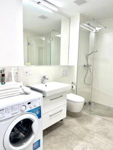 ein Badezimmer mit einer Waschmaschine und einem Waschbecken in der Unterkunft Moderne Erdgeschosswohnung in Augsburg