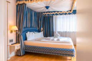 1 dormitorio con 1 cama con dosel azul en B&B Das Land-Palais - PRIVATE Mountain Hideaway, en Selva dei Molini