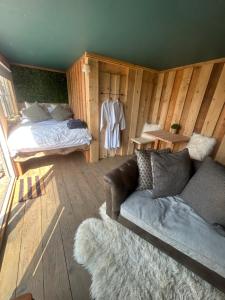 a living room with a couch and a bed at Secluded Lakeside Off Grid Cabin with Outdoor Bath in Rhosneigr