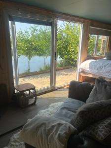 a living room with a couch in front of a window at Secluded Lakeside Off Grid Cabin with Outdoor Bath in Rhosneigr