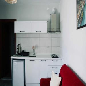 a kitchen with white cabinets and a red couch at Çeşmeli Konak in Çanakkale