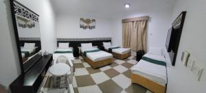 Cette chambre dispose de 4 lits et d'un sol en damier. dans l'établissement فندق مناسك الرشاد الفندقية, à La Mecque