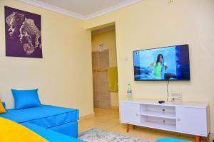 1 dormitorio con 1 cama y TV en la pared en Karibu Place Kamakis- Opp Greenspot Gardens, en Ruiru