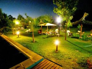 a garden with tables and umbrellas at night at Hotel y Spa Termas del Este in Federación