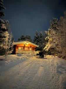 uma cabana na neve à noite com luzes acesas em Macktunet - Retro log cabin from the 70s in Malangen 