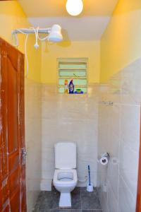 a bathroom with a toilet and a yellow wall at Karibu Place Kamakis- Opp Greenspot Gardens in Ruiru