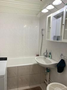 a white bathroom with a sink and a bath tub at Atomcity Apartman in Paks