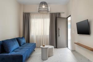 a living room with a blue couch and a tv at Phaos Residence, Your Stylish Crete Retreat in Panormos Rethymno