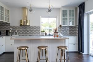 a kitchen with white cabinets and a counter with stools at The Rose Valley in Gothenburg