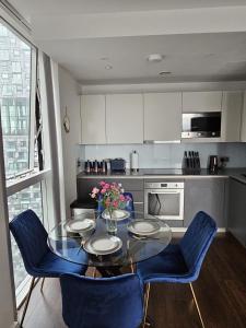 cocina con mesa de cristal y sillas azules en 2 bed Luxurious apartments Canary Wharf en Londres