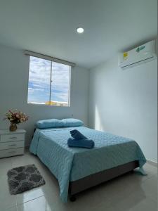 um quarto com uma cama com um cobertor azul e uma janela em CB Apto cómodo e impecable con Aire Acondicionado em Neiva