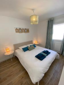 um quarto com uma grande cama branca com almofadas azuis em COSY CONFORT LA PEROUSE 1A coeur de ville et plage em Concarneau