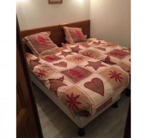 a bed with a quilt and pillows on it at Chalet d'Orcières T2 4pers. in Orcières